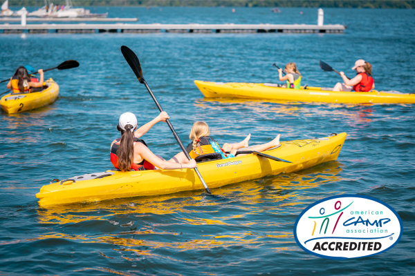 Camp counselor and camper in a two-seater kayak on Lake Mendota.